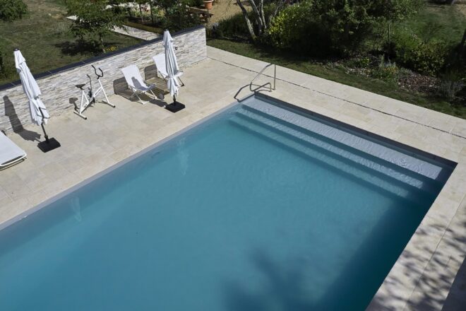 Piscine avec liner gris clair et margelles en pierres Prieuré